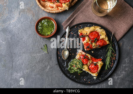 Focaccia italienne savoureuse et basilic sur table gris Banque D'Images