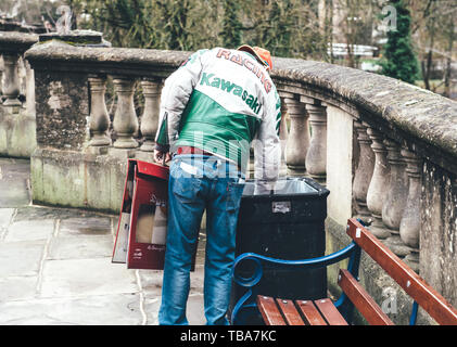 Oxford, Royaume-Uni - 3 Mar 3017 : vue arrière de sans-abri qui le porte Kawasaki Racing Veste en cuir à la recherche de nourriture dans les ordures poubelle Banque D'Images