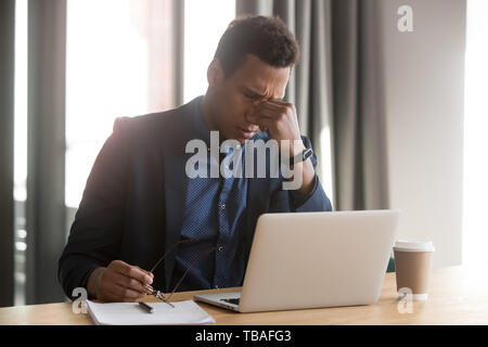 Fatigué black businessman enlever verres souffrant de maux de tête Banque D'Images