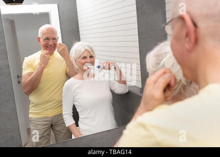 Les personnes âgées avec le brossage des dents et la soie dentaire. Matin dans la salle de bains Banque D'Images