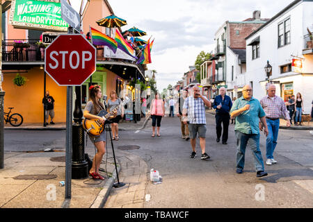 New Orleans, USA - 22 Avril 2018 : Street en Louisiane célèbre ville ville en soirée avec de jeunes fille femme jouant de la guitare dans la nuit et les gens qui marchent Banque D'Images