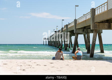 Fort Walton Beach, États-Unis - 24 avril 2018: Les gens, couple assis sur la plage de sable à l'île d'Okaloosa jetée de pêche avec des vagues de mer d'océan au golfe de moi Banque D'Images