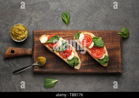 Planche de bois avec des bruschettas savoureux sur fond gris Banque D'Images