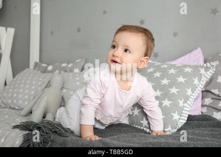 Cute baby girl crawling on bed Banque D'Images