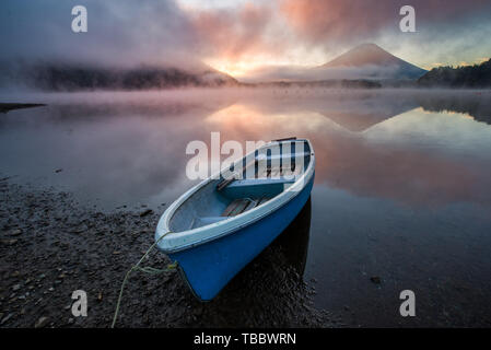 Beau lever de soleil au lac Shōji mystique avec le Mont Fuji en toile de fond et un bateau à rames en premier plan Banque D'Images