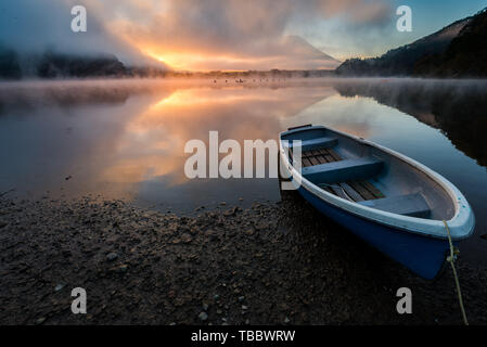 Beau lever de soleil au lac Shōji mystique avec le Mont Fuji en toile de fond et un bateau à rames en premier plan Banque D'Images