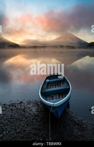 Beau lever de soleil au lac Shōji mystique avec le Mont Fuji en toile de fond et un bateau à rames en premier plan Banque D'Images