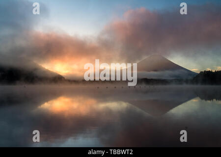 Beau lever de soleil au lac Shōji mystique avec le Mont Fuji en toile de fond et un bateau à rames en premier plan Banque D'Images