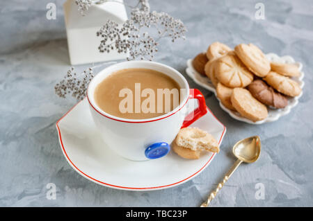 Chocolat chaud le matin dans la tasse blanche originale avec un bouton bleu sur le fond de biscuits. Le petit-déjeuner revigorant. Banque D'Images