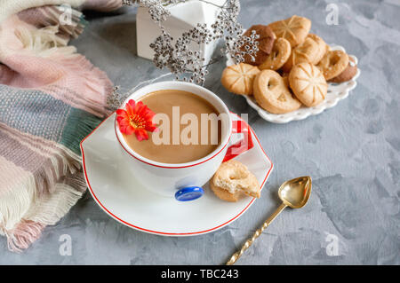 Chocolat chaud le matin dans la tasse blanche originale avec un bouton bleu sur le fond de biscuits. Le petit-déjeuner revigorant. Banque D'Images