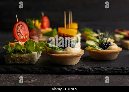 Plaque en ardoise avec de savoureux canapés sur tableau noir, gros plan Banque D'Images