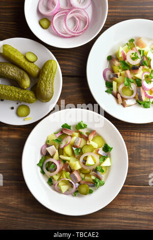 Salade de Harengs aux pommes de terre, oignon, concombre mariné et pomme sur table en bois. Haut de la vue, télévision lay Banque D'Images