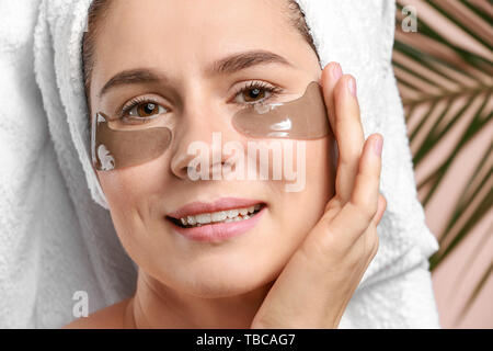 Femme avec sous-eye patches sur un fond de couleur, gros plan Banque D'Images