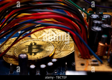 Cryptocurrency virtuelle Bitcoin argent pièces d'or sur un ordinateur de circuits imprimés PCB entouré par différents câbles colorés. L'avenir de l'argent Banque D'Images