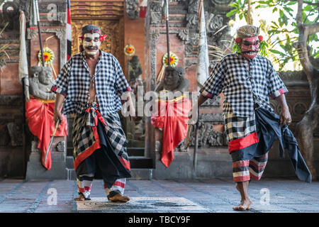 Banjar Gelulung, Bali, Indonésie - 26 Février 2019 : Mas de village. Jouer sur scène. Deux bandits habillés de danse avec chemises à carreaux gris-blanc. Banque D'Images