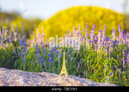 Image lumineuse d'une tour Eiffel miniature avec des champs de lavande en arrière-plan à jour . la culture française . Banque D'Images