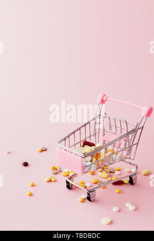 Panier du supermarché plein de pilules et drogues sur un fond rose. Les achats de médicaments, l'achat sur Internet. Télévision Banque D'Images