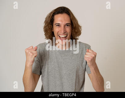 Portrait de jeune homme très excité la célébration de gagner à la loterie ou d'avoir beaucoup de succès. Adolescent avec des cheveux longs et surpris et heureux des gestes. Banque D'Images