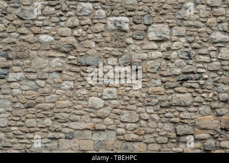 Couleur gris Modèle de conception de style ancien en pierre décorative fissuré inégale à la surface du mur avec du ciment. Vieux Mur de pierre beige background texture. Partie de Banque D'Images