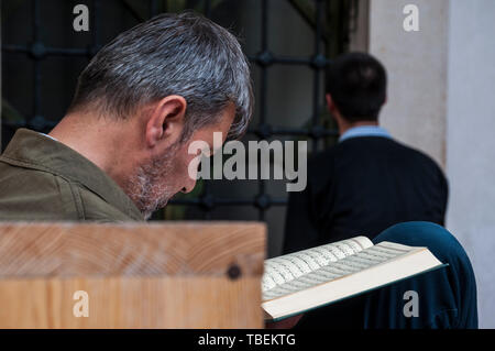 Sarajevo, Bosnie : un musulman lire le Coran à proximité d'un frère de prier en direction de La Mecque à l'extérieur de la mosquée Gazi Husrev-beg (1532) Banque D'Images