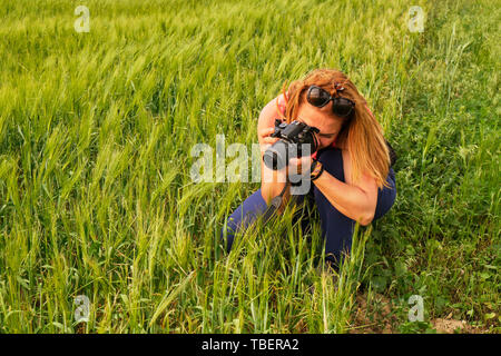 Montagnes Macin, Dobrogea, Roumanie - 18 mai 2019 : Femme photographe de prendre des photos d'un angle faible champ de seigle, à l'heure d'or, avec une lumière chaude. Banque D'Images