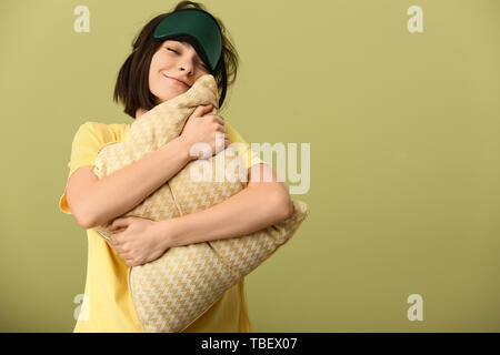 Heureux jeune femme avec un masque de sommeil et l'oreiller sur un fond de couleur Banque D'Images