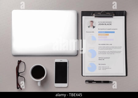 Reprendre d'emploi avec un ordinateur portable, téléphone mobile et tasse de café sur fond gris Banque D'Images