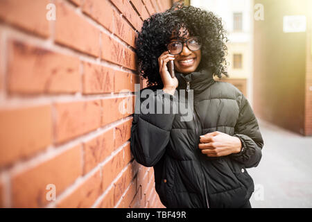 Portrait de jolie femme noire de fond urbain en parlant au téléphone Banque D'Images