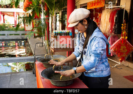 Femme thaïlandaise se frotter à poignée de laiton lavabo de style chinois pour la bénédiction et la chance à Thai-Chinese Centre culturel le 19 décembre 2017 à Udon Thani, Banque D'Images