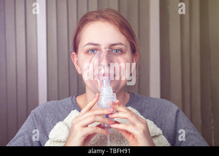 Jeune femme adulte de fibrose pulmonaire idiopathique fait inhalation avec masque nébuliseur. Banque D'Images
