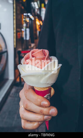 Vue rapprochée de mans hand holding ice cream rose en forme au marché de nuit Banque D'Images