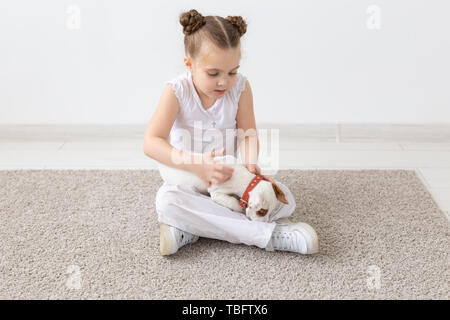 Les enfants, animaux domestiques et animaux - concept fille enfant jouer avec son Jack Russell Terrier puppy à l'intérieur Banque D'Images