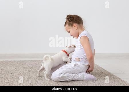 Animal de compagnie, les enfants et animaux - concept enfant fille assise sur le sol et l'alimentation chiot Banque D'Images