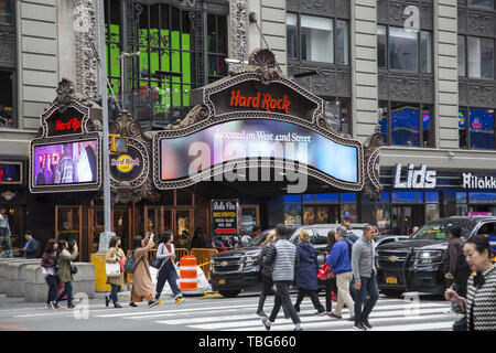 Les gens traversent à l'angle de Broadway et de la 43e Rue par le célèbre Hard Rock Café de Times Square et le quartier des théâtres, dans midtown Manhattan, New York. Banque D'Images