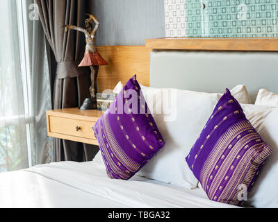 Purple pillow sur lit blanc, gros plan tourné. Banque D'Images