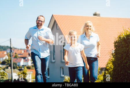 Famille heureuse courir devant leur nouvelle maison Banque D'Images