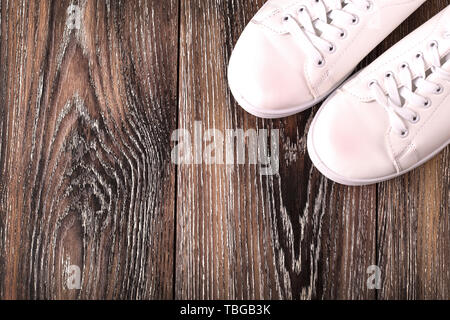 Baskets blanc sur la surface en bois sombre. Chaussures pour femmes en sport fashion style. Banque D'Images