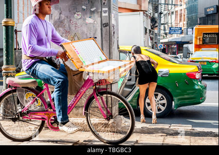 Un vendeur de billets de loterie voyages par Bangkok sur sa bicyclette pour vendre des billets sur Sukhumvit Road en Thaïlande. Banque D'Images