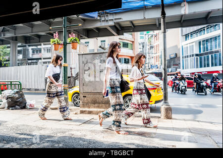 3 touristes asiatiques font leur chemin à travers le quartier animé de Sukhumvit Road Bangkok, Thaïlande. Banque D'Images