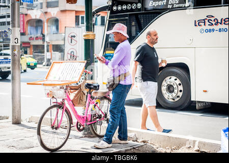 Un vendeur de billets de loterie voyages par Bangkok sur sa bicyclette pour vendre des billets sur Sukhumvit Road en Thaïlande. Banque D'Images