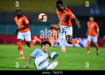 Joueur de football Kenyan Ayub Masika, haut, de Pékin Renhe passe le ballon contre un joueur de Tianjin Tianhai dans leur 12e match au cours de l'Association de football chinoise 2019 Super League (CSL), à Beijing, Chine, 1 juin 2019. Renhe Beijing Tianjin Tianhai défait 2-0. Banque D'Images