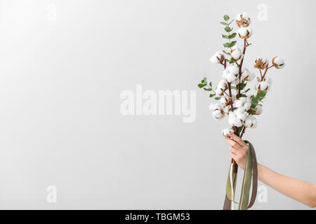 Femme hand holding composition florale avec fleurs de coton sur fond clair Banque D'Images