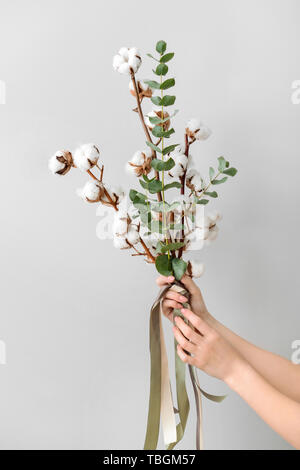 Les mains tenant composition florale avec fleurs de coton sur fond clair Banque D'Images