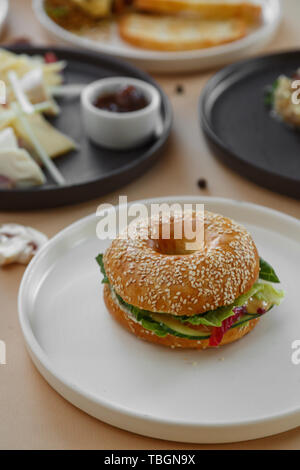 Bagels avec crème, avocat, saumon, tomates sur fond beige table. Petit déjeuner d'un sain Banque D'Images