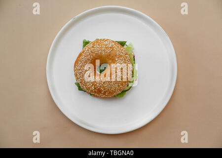 Bagels avec crème, avocat, saumon, tomates sur fond beige table. Petit déjeuner santé alimentation. Vue d'en haut Banque D'Images