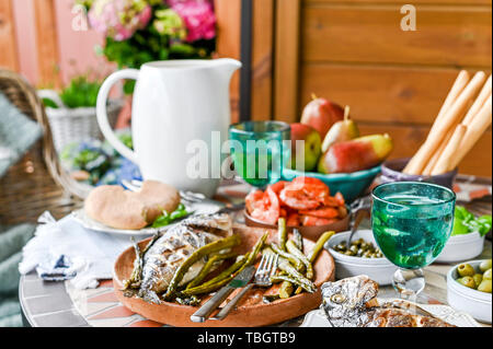 Table à manger avec des aliments différents, des collations et des fleurs. Le déjeuner d'été en plein air. Des fruits de mer et des légumes. Banque D'Images