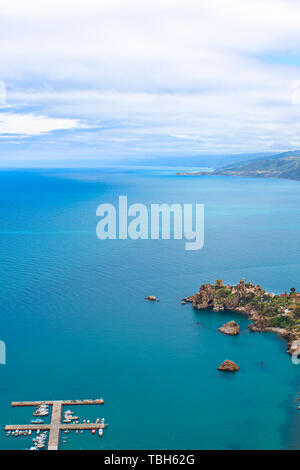 L'eau calme bleu foncé de la mer Tyrrhénienne entourant le village côtier de Sicile Cefalu à partir de ci-dessus. Capturé sur Photo verticale avec Pier et de bateaux dans la mer. Banque D'Images