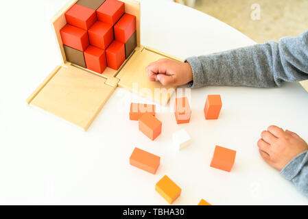 Les mains de l'enfant apprendre à mettre en place les pièces d'un puzzle en bois 3d. Banque D'Images