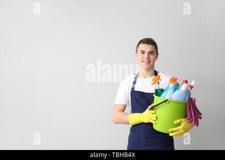 Portrait of male janitor avec produits de nettoyage sur fond clair Banque D'Images