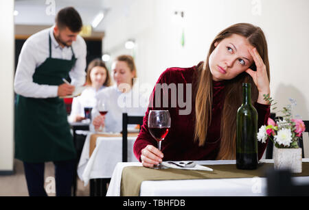 Femme élégante en colère s'attend à ce que l'homme pour le dîner dans le restaurant de luxe intérieur. Banque D'Images